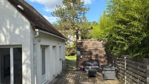 A patio with a table and chairs, a wooden fence, and a white building with a window. - "Les 2 Marmottes" your charming gîte in Essonne (Buno-Bonnevaux)