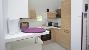 A compact kitchen with white countertops, a microwave, a coffee maker, and wooden cabinets. - "Les 2 Marmottes" your charming gîte in Essonne (Buno-Bonnevaux)