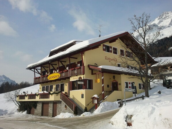 A two-story building with a yellow facade, a balcony with red railings, and a sign that reads "REINERHOF."