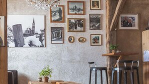 En rustik inredning med ett stort inramat fotografi av ett snötäckt landskap, trästolar vid bardisken och en kristallkrona.