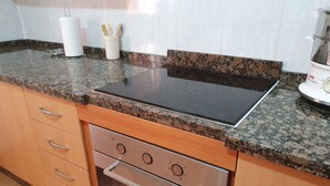 A kitchen with a granite countertop, stainless steel oven, and wooden cabinets. - Casa Rural El Patio, with private pool (Fuente de Piedra)