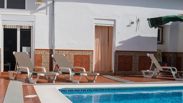 A swimming pool with lounge chairs and a tiled deck. - Casa Rural El Patio, with private pool (Fuente de Piedra)