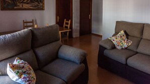 A living room with two sofas, a dining table, and chairs. There is a painting on the wall and a door with a white frame. - Casa Rural El Patio, with private pool (Fuente de Piedra)