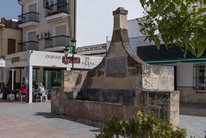 A stone structure with a chimney, a cafe named 'COPAS BOLI PLAZA' with outdoor seating, and a building with balconies in the background. - Casa Rural El Patio, with private pool (Fuente de Piedra)