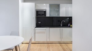 A modern kitchen with white cabinets, a black countertop, and a built-in oven. - Beautiful 1 bedroom apartment (Croydon)