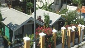 Zona residencial con casas, una entrada con portón y una calle.