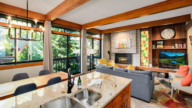 Eine moderne Küche mit Granit-Arbeitsplatten, einer integrierten Spüle und einem Essbereich mit Holztisch und Stühlen.