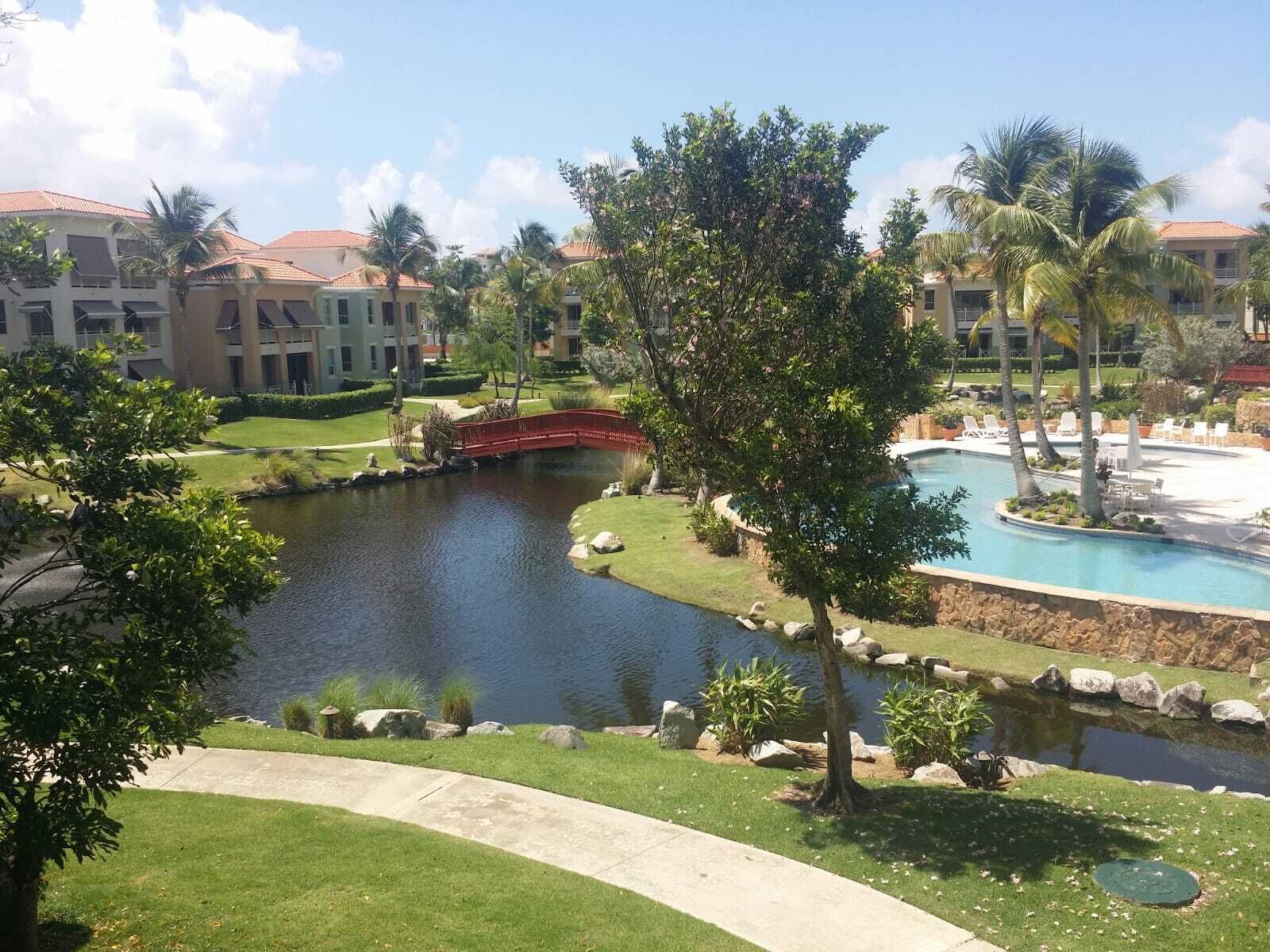 Un resort con piscina, un lago pequeño y un puente.