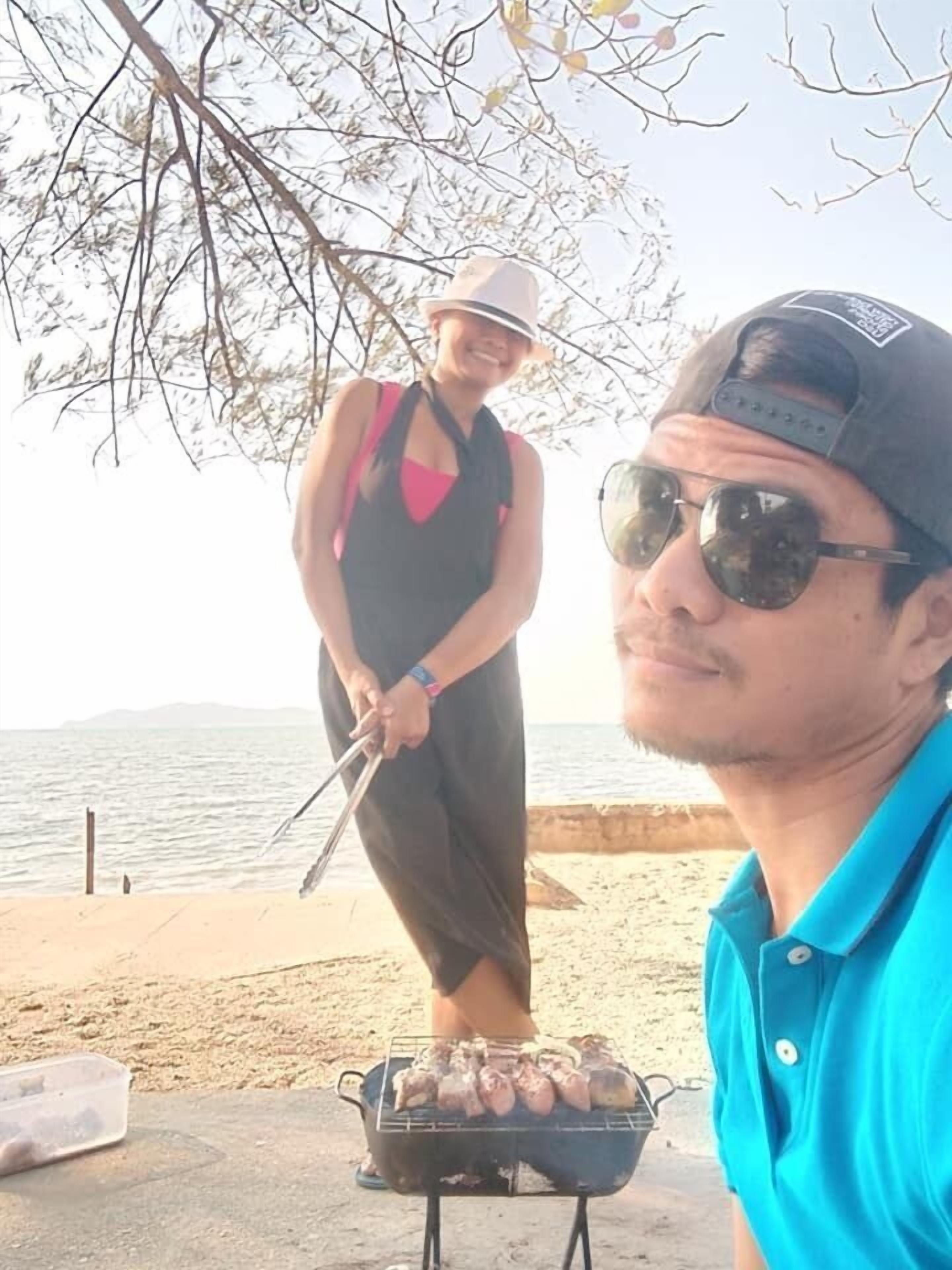 A person grilling outdoors near a body of water.