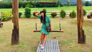 A wooden swing set with a metal platform in a grassy field with a mountain in the background. - Smile Home Guesthouse (Rayong)