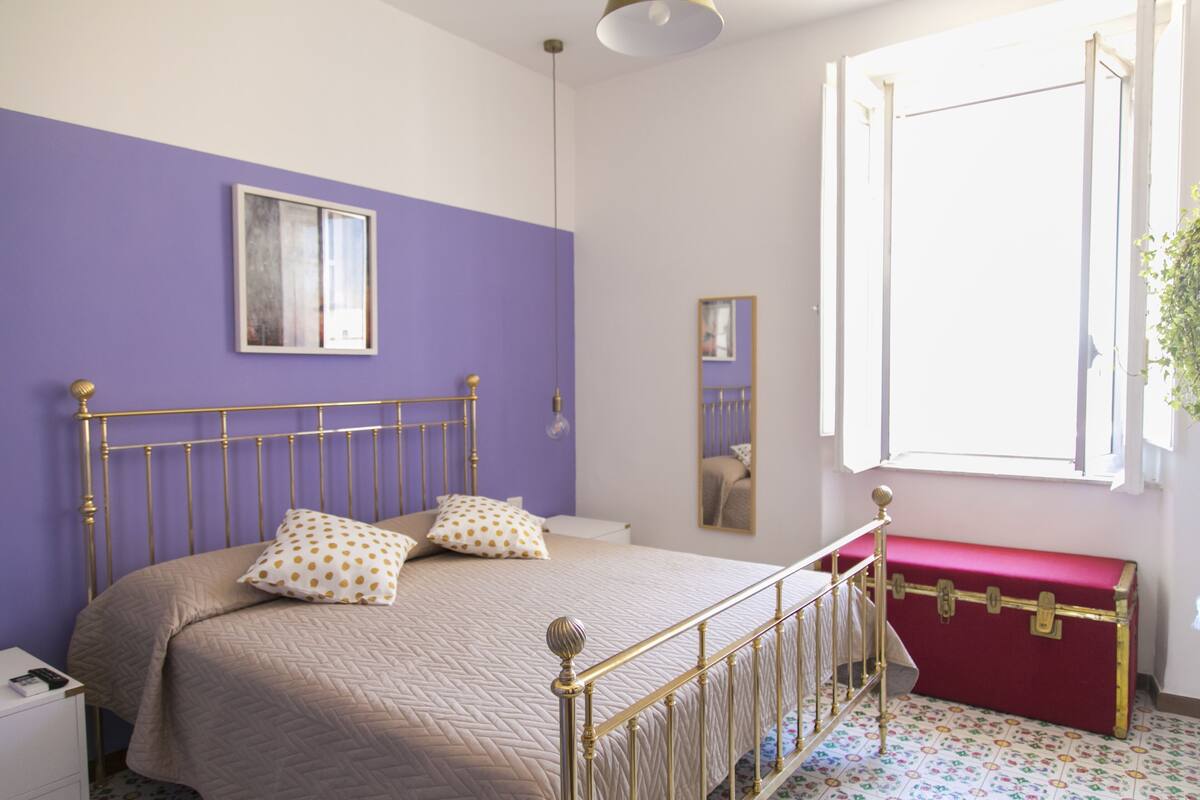 Une chambre à coucher avec un lit, une commode, une fenêtre et un miroir.