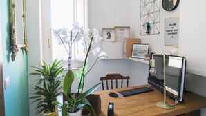 Un bureau en bois avec un ordinateur, un clavier, une souris et une plante en pot.