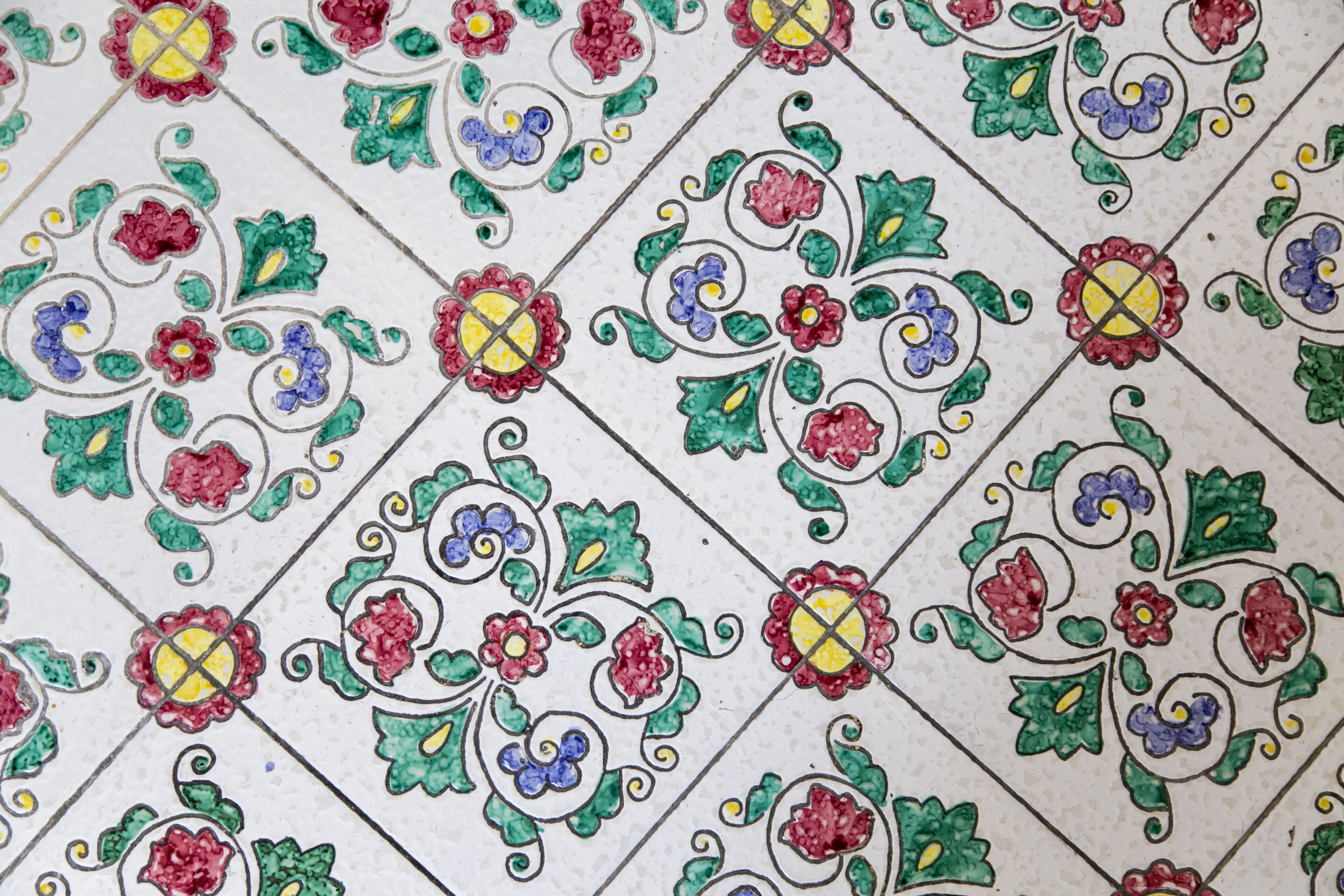 A tiled floor with a geometric pattern of floral designs in red, blue, and green colors.