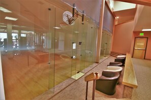 A gym with exercise equipment, a glass wall, and a reception desk.