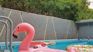 Una piscina con juguetes inflables, incluyendo un flamenco rosa y un flotador de colores.