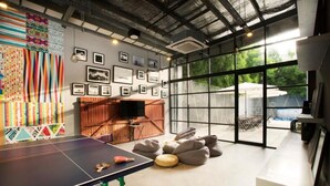 A ping pong table, bean bags, and a TV in a room with large windows and a view of the outdoors. - The Social House - Coliving & Hostel (Jakarta)