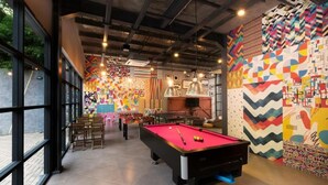 A billiards room with a pool table, chairs, and colorful wall art. - The Social House - Coliving & Hostel (Jakarta)
