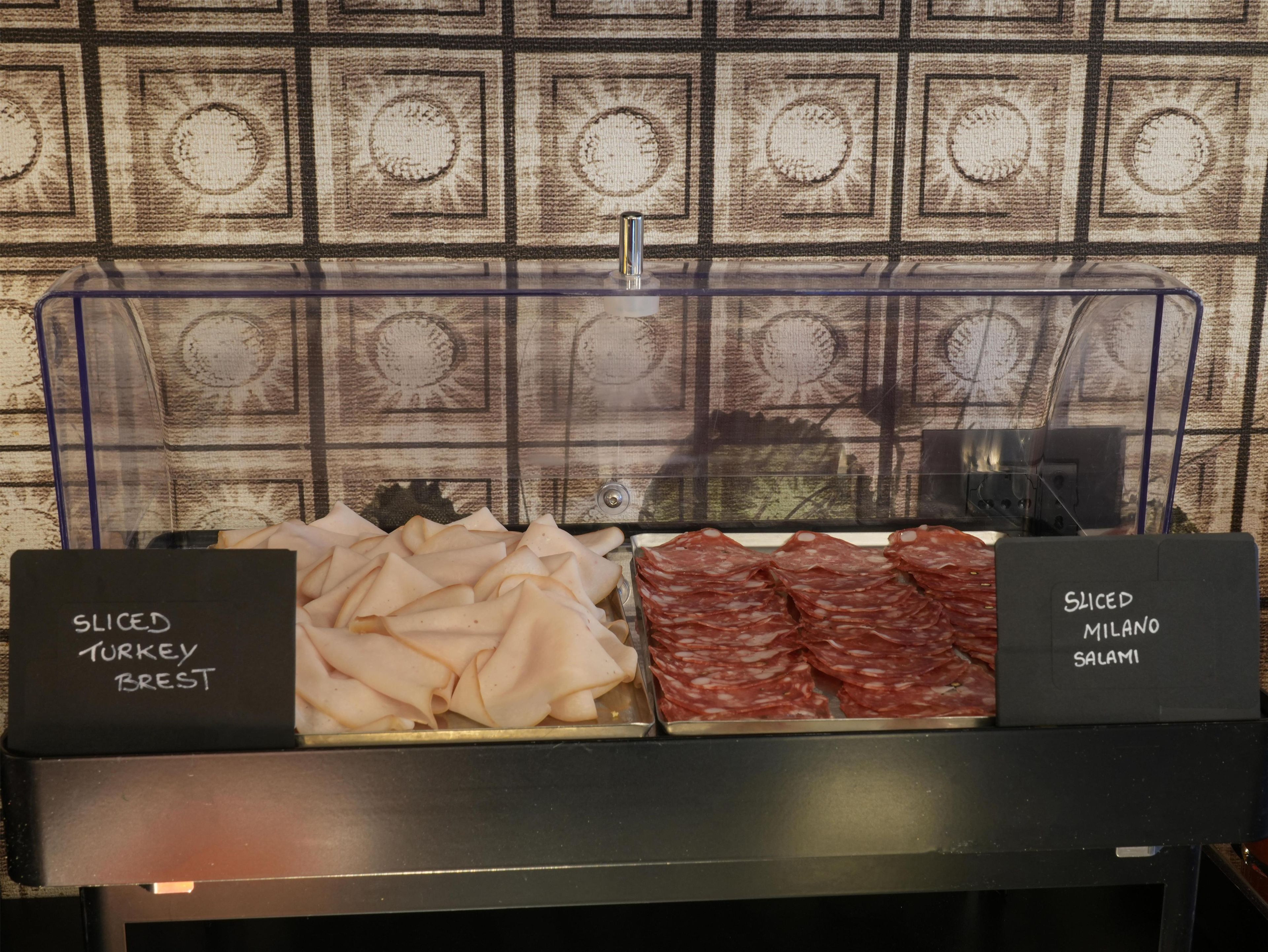 A display case with sliced turkey breast and sliced salami.