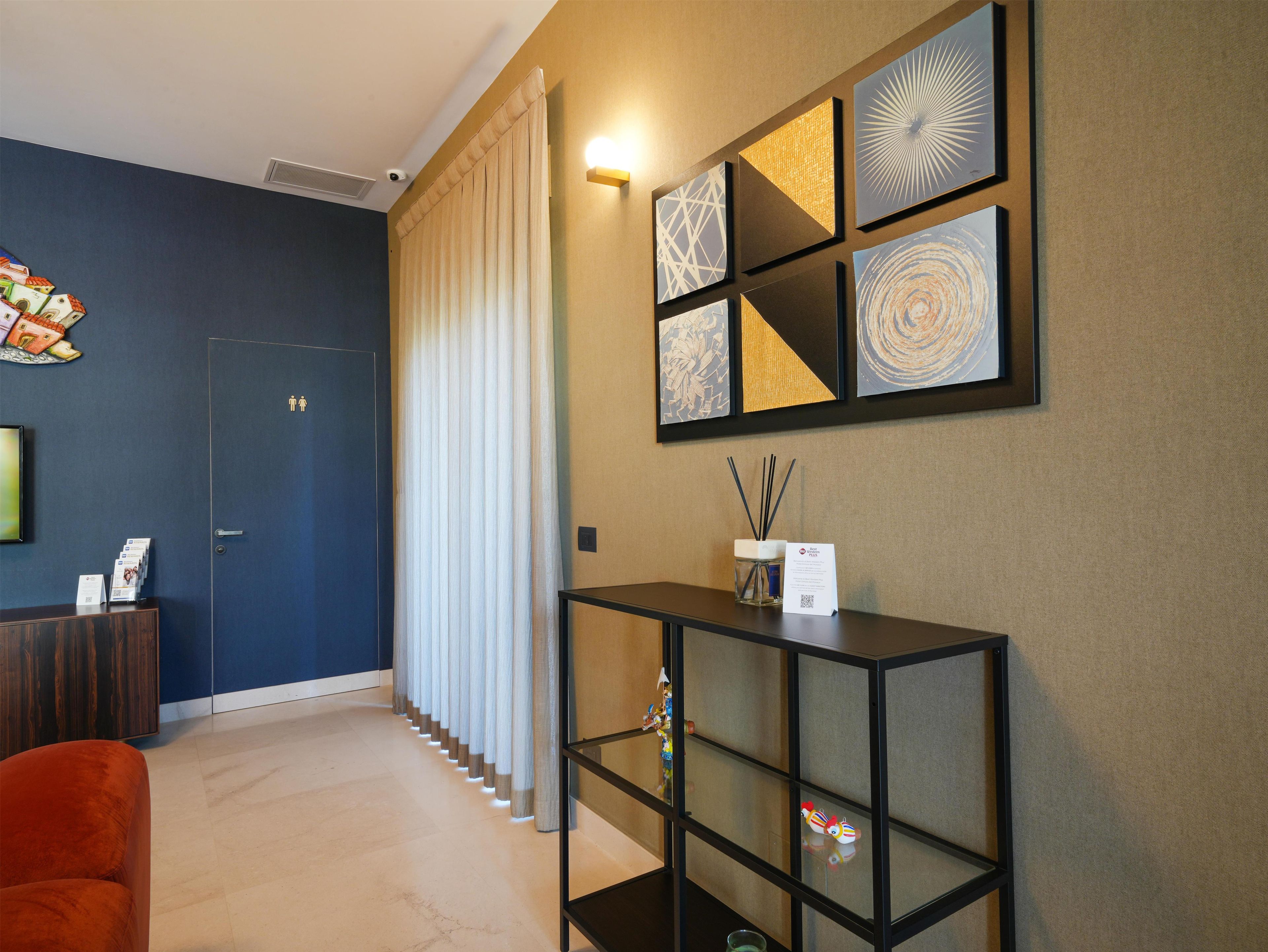 A hotel lobby with a reception desk, a seating area, and a wall with framed artwork.