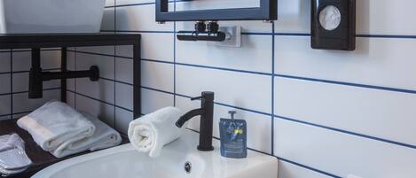 A bathroom with a white sink, a towel rack, a soap dispenser, and a toilet paper holder on the wall.