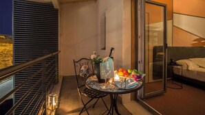 Een balkon met een eettafel, een stoel, een kleine potplant en een kaars.