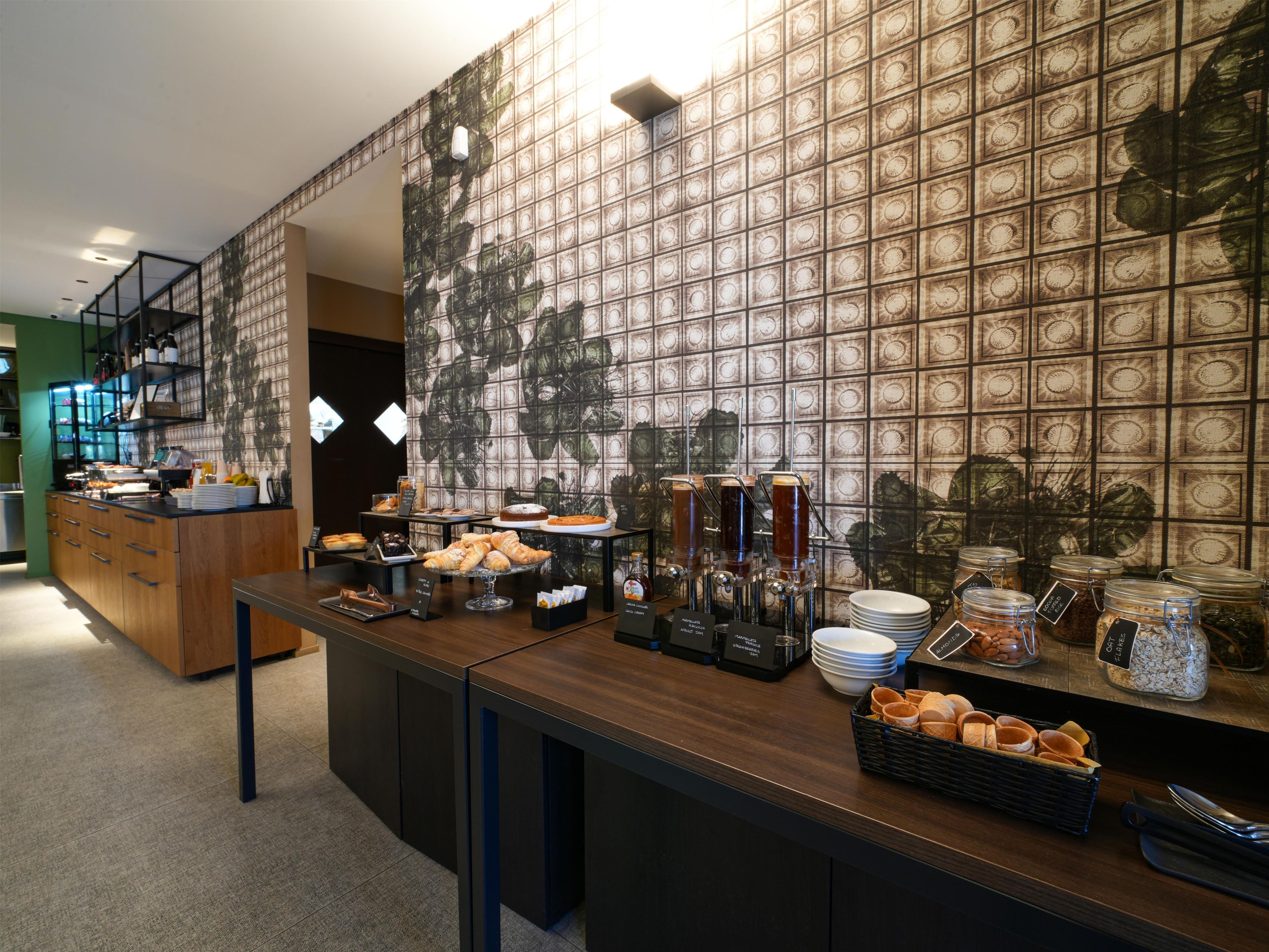 A breakfast buffet with various food items and beverages, a coffee station, and a counter with utensils.
