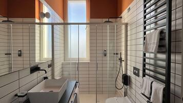 Un baño moderno con dos lavamanos, ducha e inodoro.