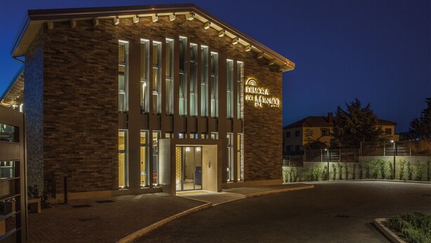 Een modern gebouw met een stenen gevel, grote ramen en een goed verlichte ingang.