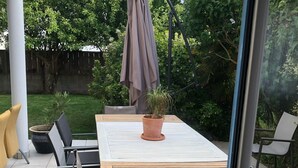 An outdoor patio with a table and chairs, a potted plant, and a hanging umbrella. - House close to the beach (Carnac)