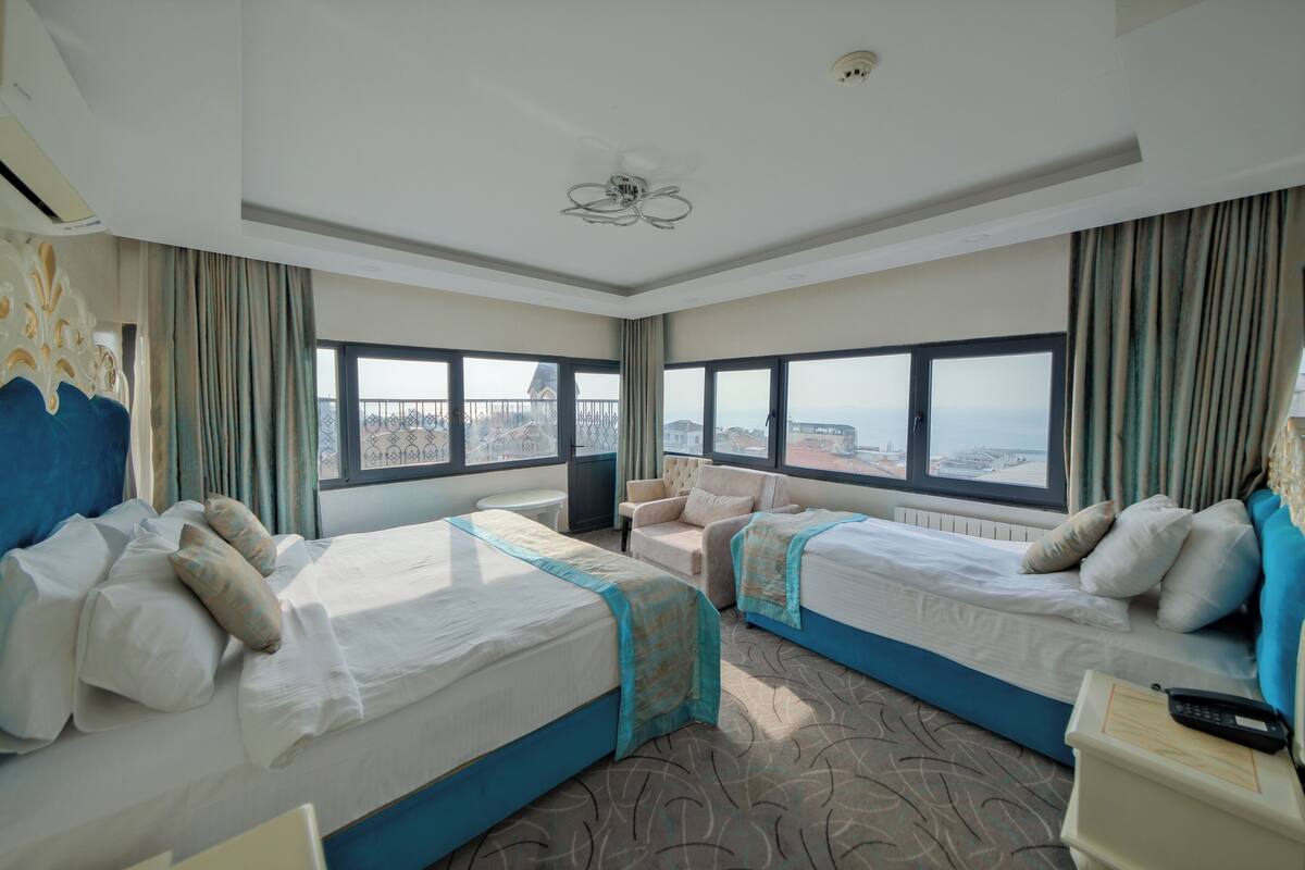 A hotel room with two beds, a view of the city, and a balcony.