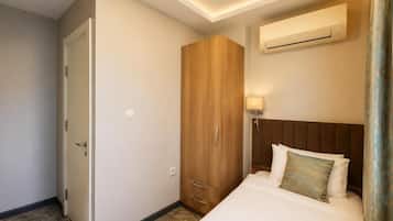 Una habitación de hotel con cama, armario, equipo de aire acondicionado y lámpara de pared.