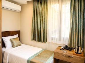 A hotel room with a bed, a bedside table with a phone, a kettle, and curtains. - Grand Kavi Hotel (Istanbul)