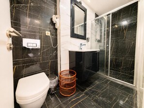 A bathroom with a toilet, sink, mirror, and shower area. - Grand Kavi Hotel (Istanbul)