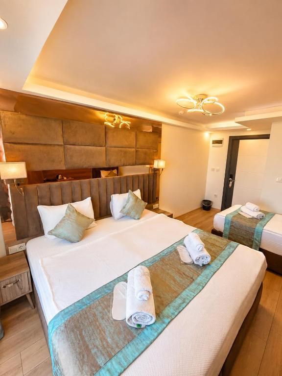A hotel room with two beds, a headboard, bedside lamps, and a wall-mounted light fixture.