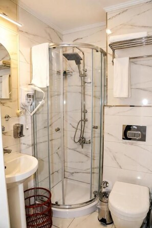 A modern bathroom with a glass-enclosed shower, a white sink, and a toilet. - Grand Kavi Hotel (Istanbul)