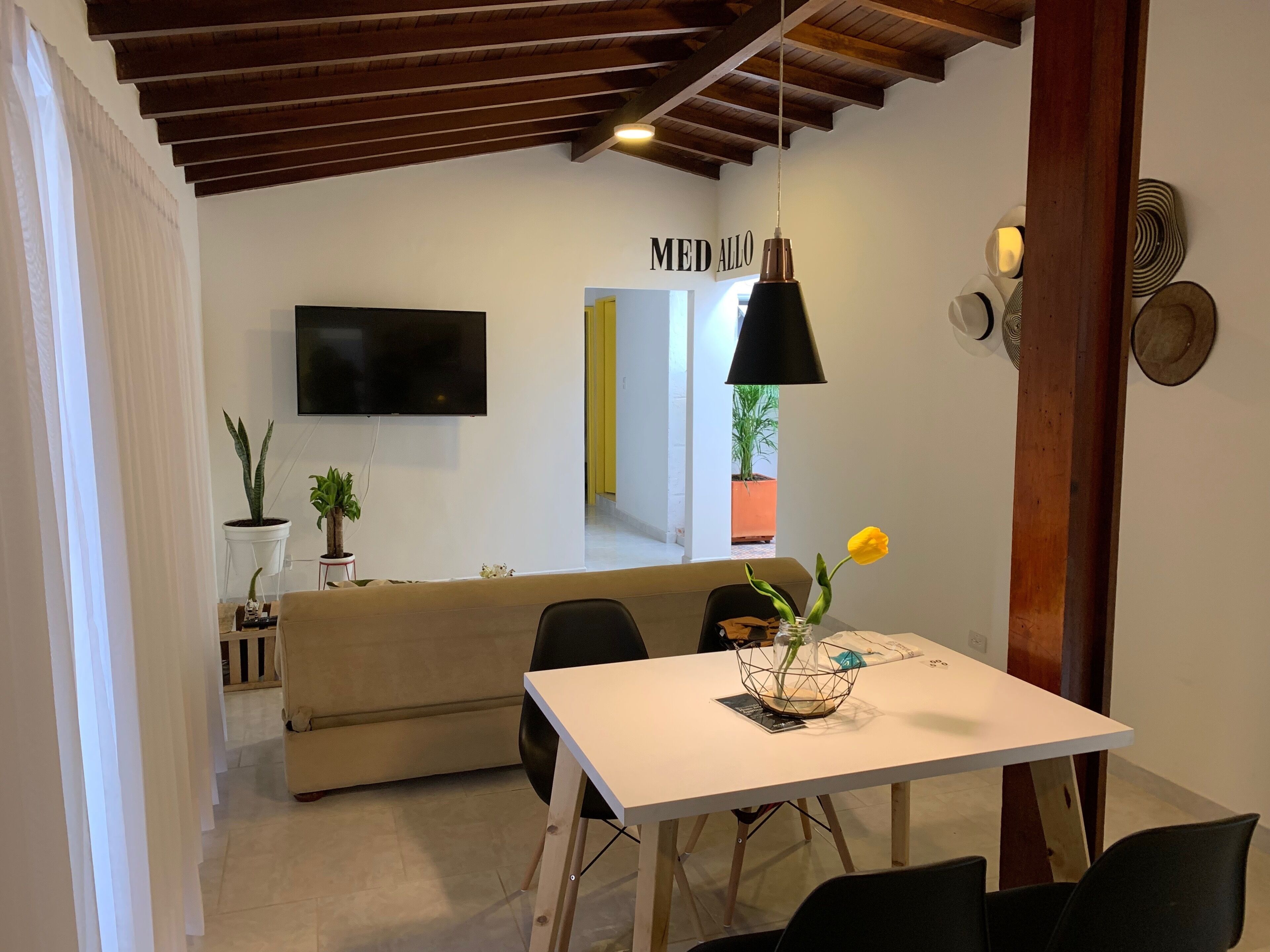 Una sala de estar moderna con un sofá, una mesa de comedor y un televisor montado en la pared.