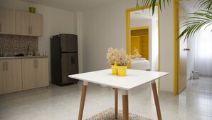 Una cocina moderna con una mesa blanca, patas de madera y piso de baldosas.