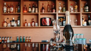 A bar with a variety of liquor bottles on shelves and a bottle of champagne on the counter. - Bayil Breeze Hotel (Baku)