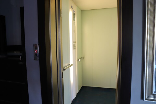 A narrow hallway with a door on the left, a light switch, and a wall-mounted light fixture. - Albergo Cantiani (Ancona)