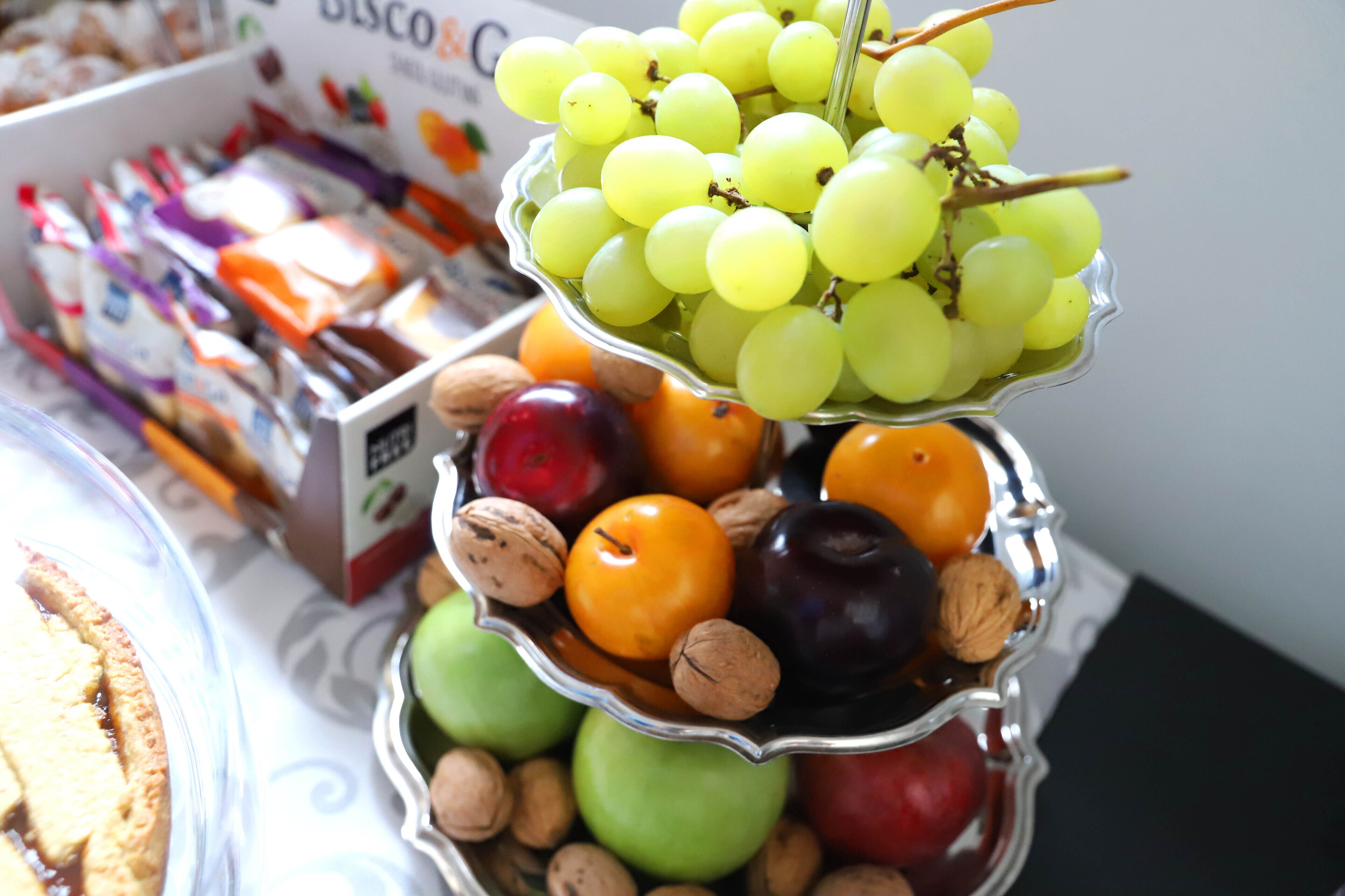 Une présentation en étages de fruits et de fruits secs, avec des pommes, des noix et des raisins.