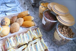 A buffet table with various food items including bread, cheese, and cereal. - Albergo Cantiani (Ancona)