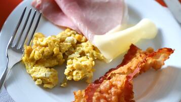 Un piatto con uova strapazzate, pancetta e burro.