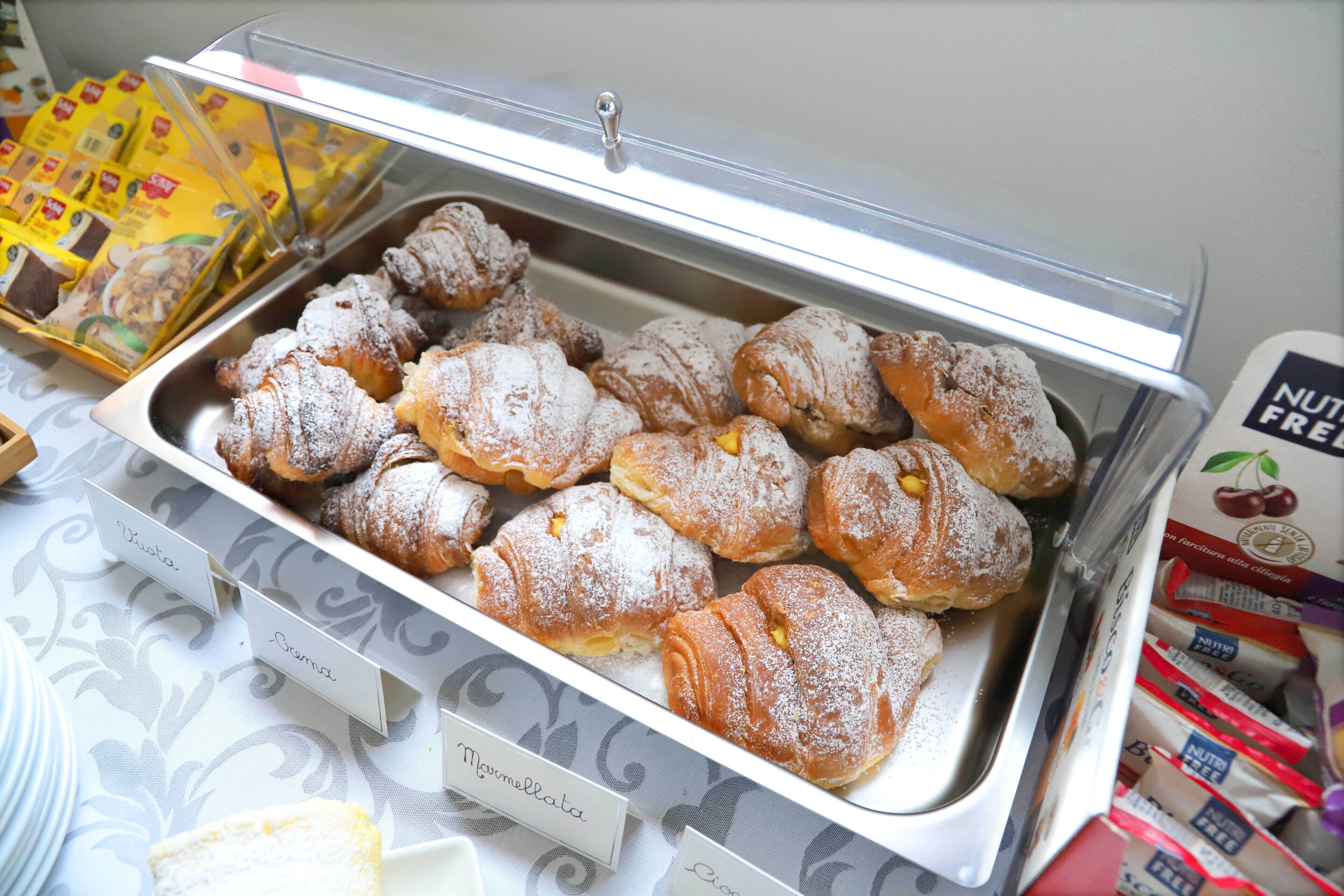 Ein Buffet mit einer Auswahl an Gebäck, darunter Cannoli und Cannoli-Schalen, mit entsprechenden Beschriftungen.