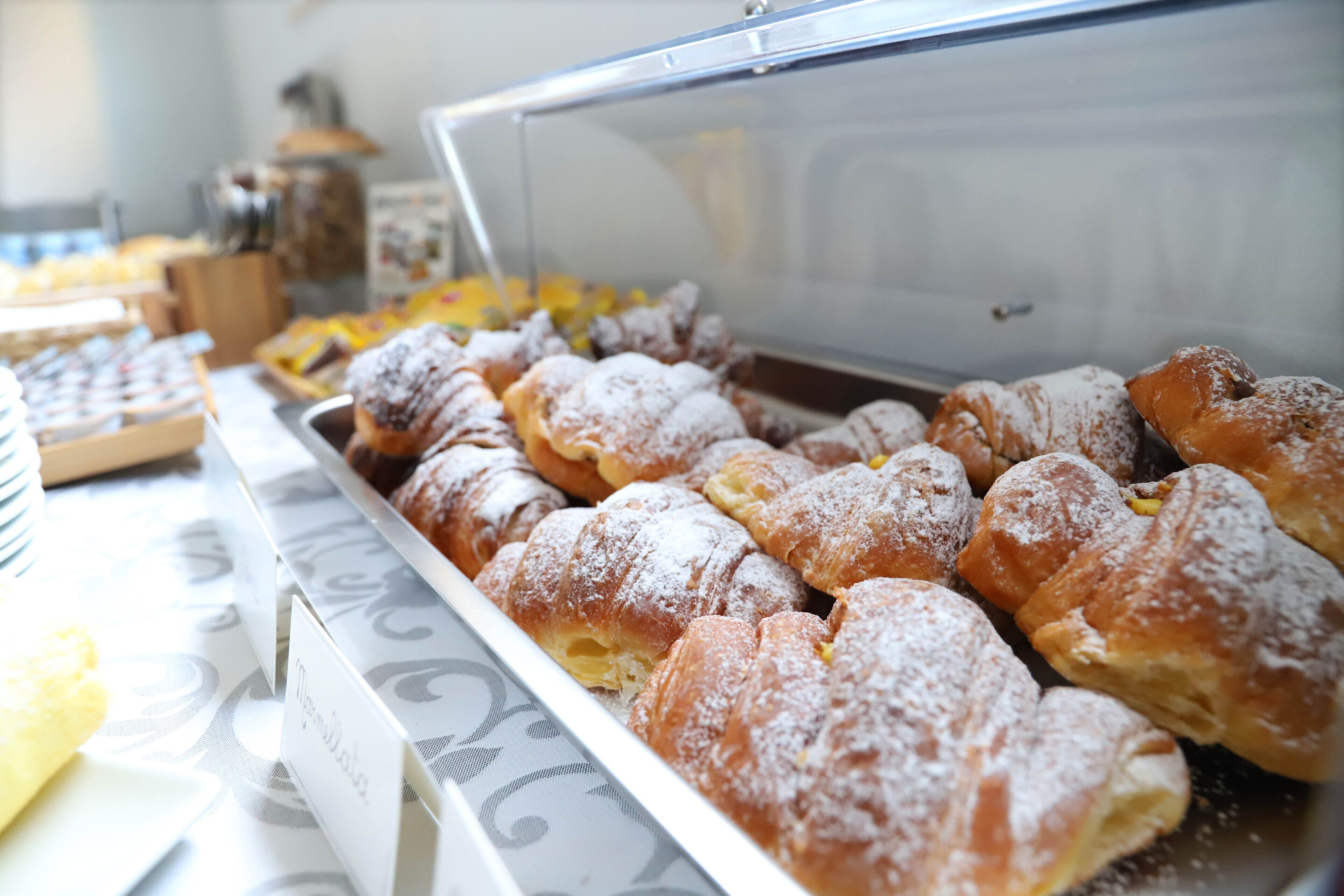 Een display met diverse gebakjes, waaronder croissants en ander vers gebakken brood.