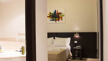 Una camera d'albergo con un letto, un comodino e un'opera d'arte appesa al muro.