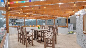 An outdoor patio with wooden tables and chairs, string lights, and a view of the cityscape. - Direct OCEANFRONT Just Remodel Myrtle Beach Resort (Myrtle Beach)