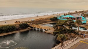 A coastal area with a wooden bridge, a beach, and a turquoise building with a pool. - Direct OCEANFRONT Just Remodel Myrtle Beach Resort (Myrtle Beach)