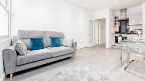 A modern living room with a grey sofa, a glass coffee table, and a white rug. - Flat 5 · Stunning 2-Bed Notting Hill Portobello Apartment (London)