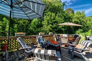 Une terrasse extérieure dotée d’un foyer, de meubles en osier et de parasols.