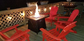 Une terrasse avec un foyer, des chaises rouges et une table avec des chaises.